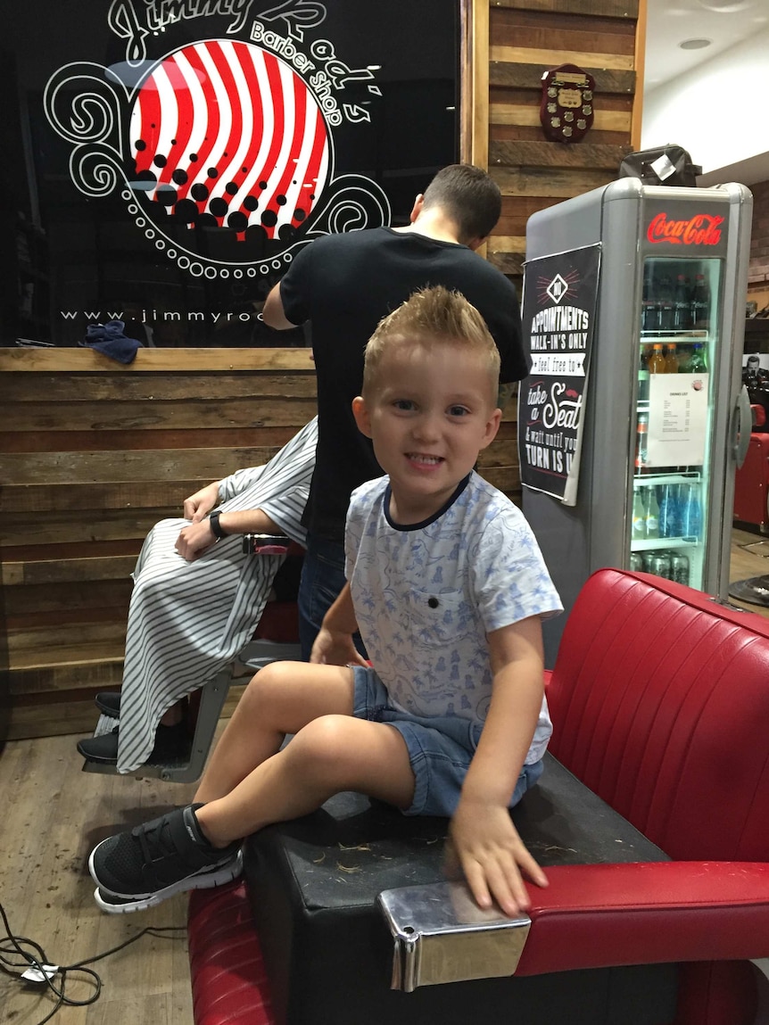 Four-year-old Angus sitting happily in the barbers' chair.