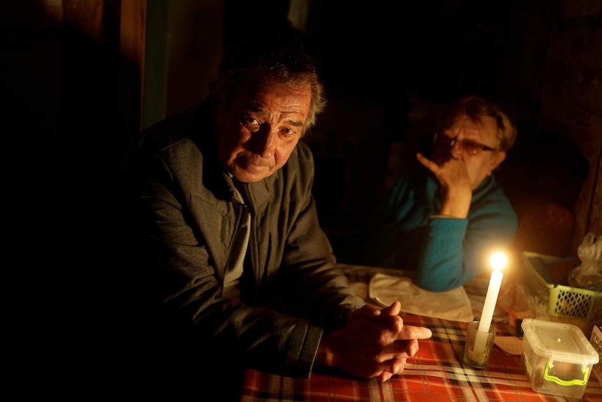 A man places his hands on a table near a candle.