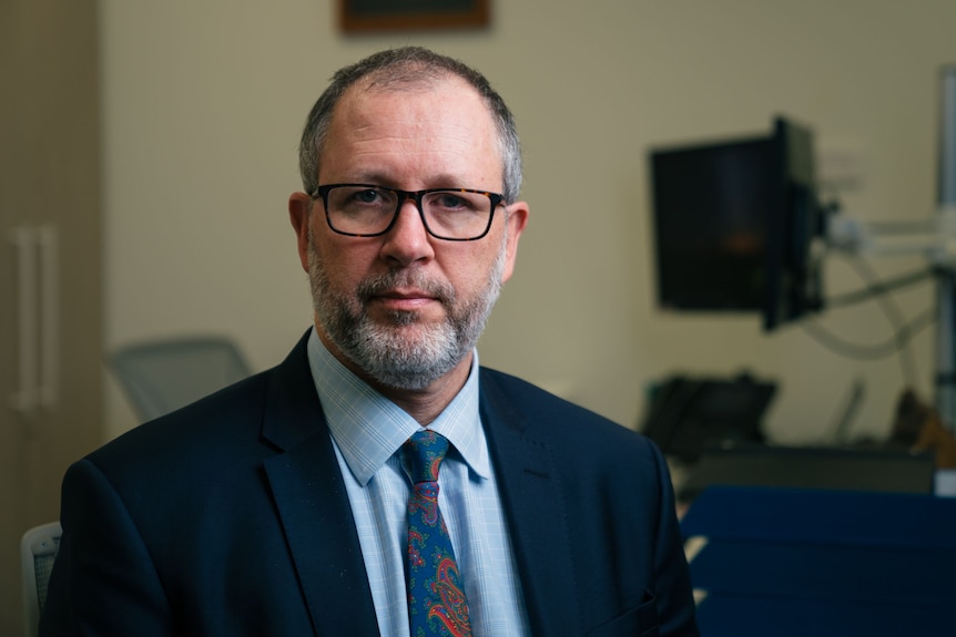 A close up of a man wearing glasses, a jacket and tie.