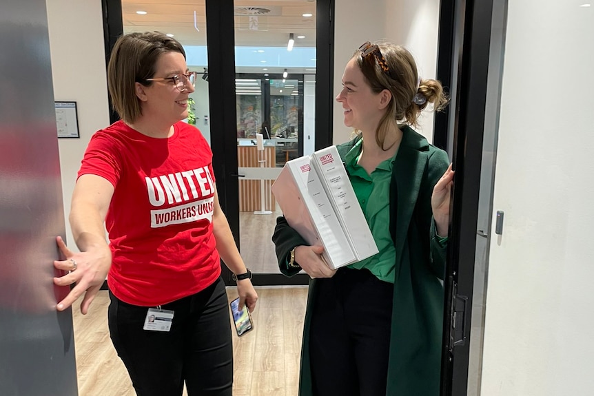 A woman wearing a red T-shirt and black pants and another woman wearing a green top and long cardigan