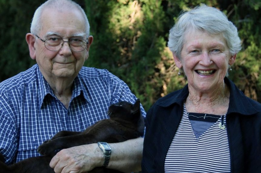 Mike Saclier stands with his wife Wendy, holding a black cat.