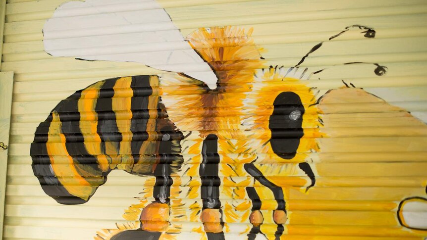 A honey bee painted onto the corrugated surface of a shop's roller door.