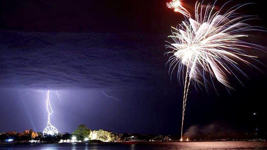 Lightning appears to strike a ferris wheel as fireworks explode during Christmas celebrations.