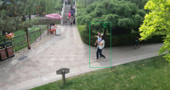 A young family is captured in a green rectangle as they walk through a park guarded by the Chinese government.