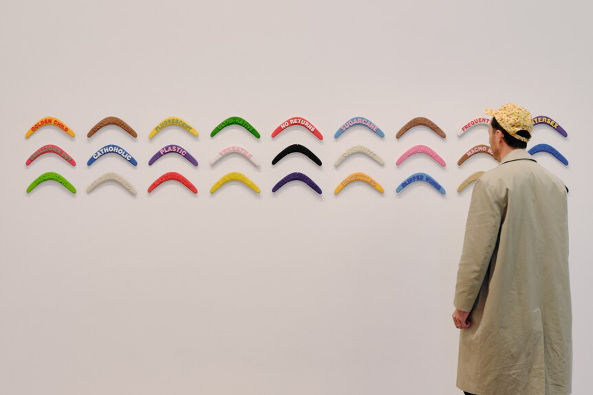 Installation view of man observing Keemon Williams' work Boomerangs on display on wall at the NGV Ian Potter Centre.