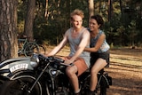 A film still of Johannes Hegemann on a 40s-style motorbike, with Liv Lisa Fries seated behind him.