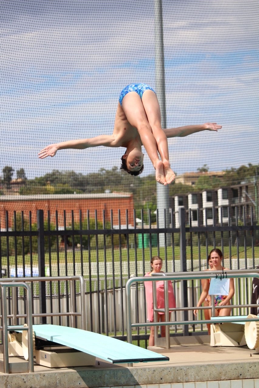 A boy with his arms out and legs together mid-air