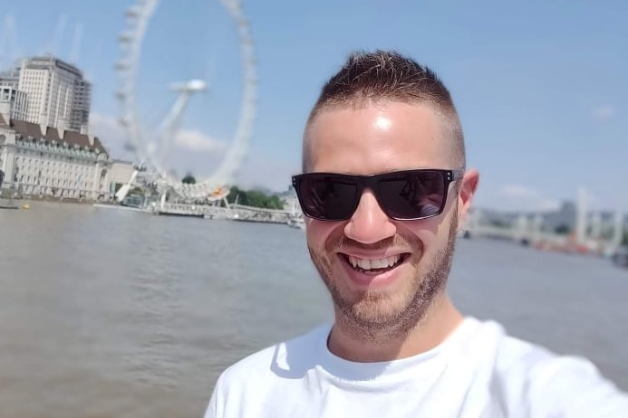 A man in glasses with a ferris wheel in the background.