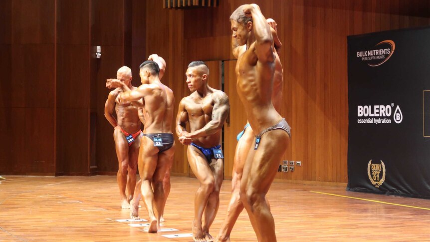 Men strike a pose on stage during the iCompete Natural Bodybuilding titles.