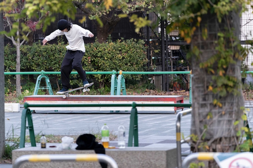A skateboarder airborne in a skate park in Japan