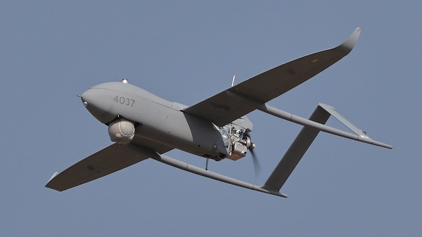 A grey drone flies through the air.