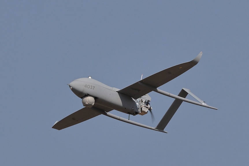 A grey drone flies through the air.
