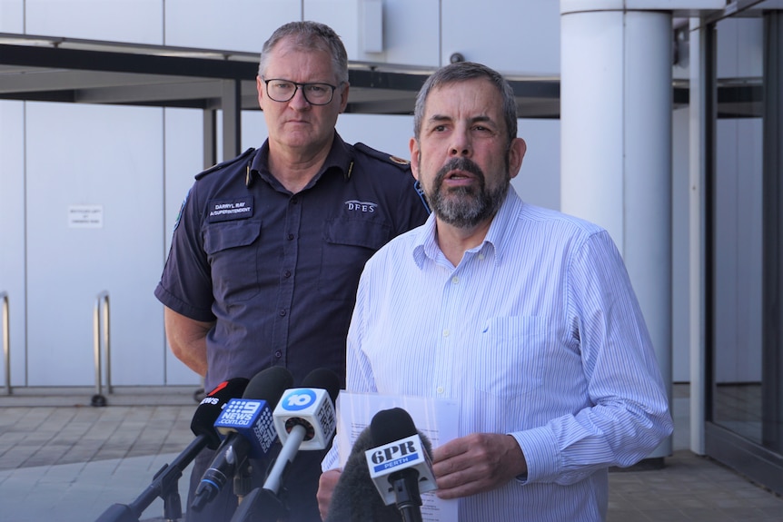 Two men standing behind media microphones 