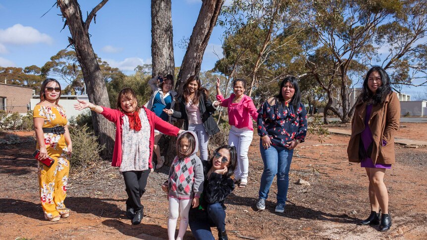 A group of Filipino women stand next to a tree in Kambalda, WA.