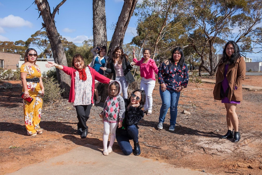 A group of Filipino women stand next to a tree in Kambalda, WA.