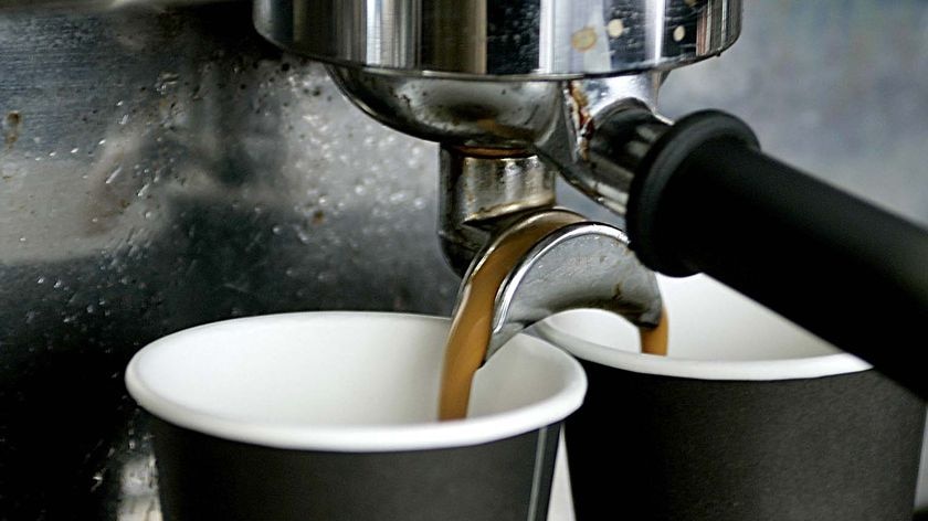 Coffee pours into cups from a machine at a coffee stand