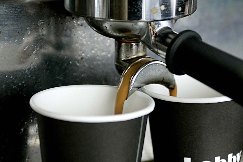 Coffee pours into cups from a machine at a coffee stand