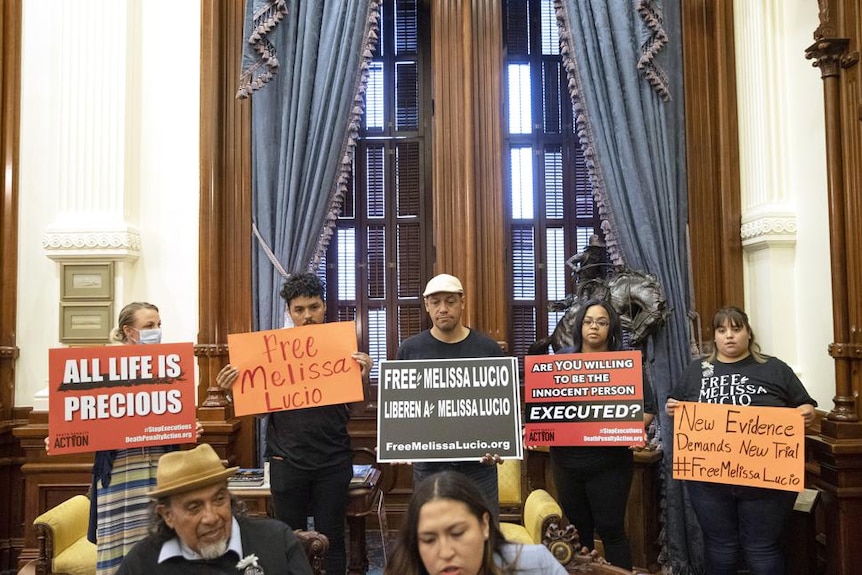 Supporters of Melissa Lucio holding signs in the Governor's Public Reception Room at the Capitol in Texas.