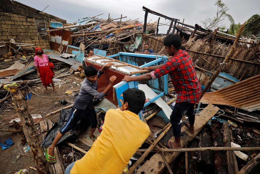People salvage their belongings from a damaged house after cyclone Tauktae hit, in Navabandar village.