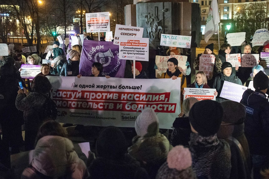 A group of women with megaphones and posters at night.