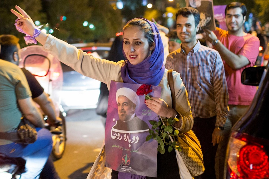 A woman wearing a hijab holds a poster of Iranian President Hassan Rouhani during a campaign rally in Tehran, Iran.