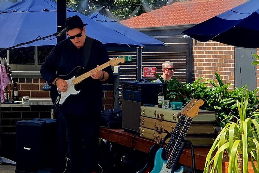 Scott Burford plays an electric guitar at an outdoor concert 