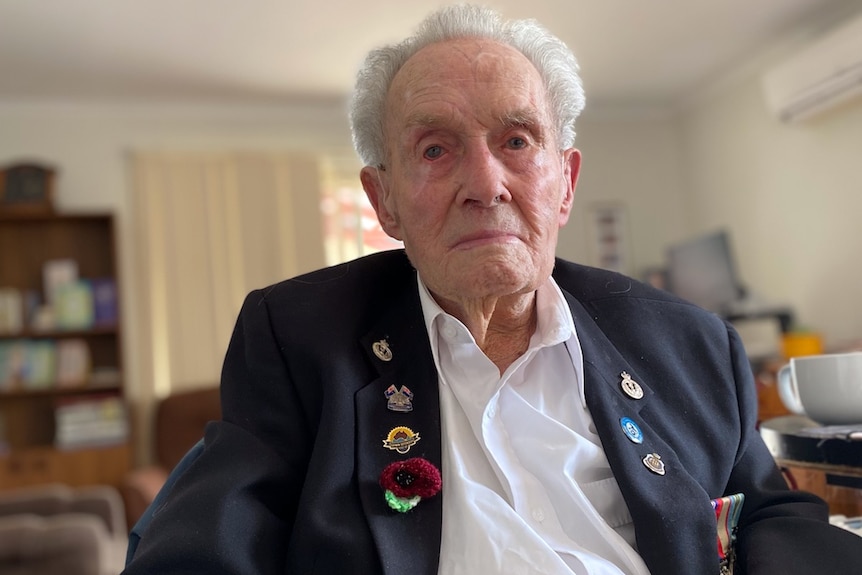 An elderly man sits with his war medals.