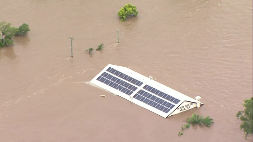 Just a roof visible in brown floodwaters.