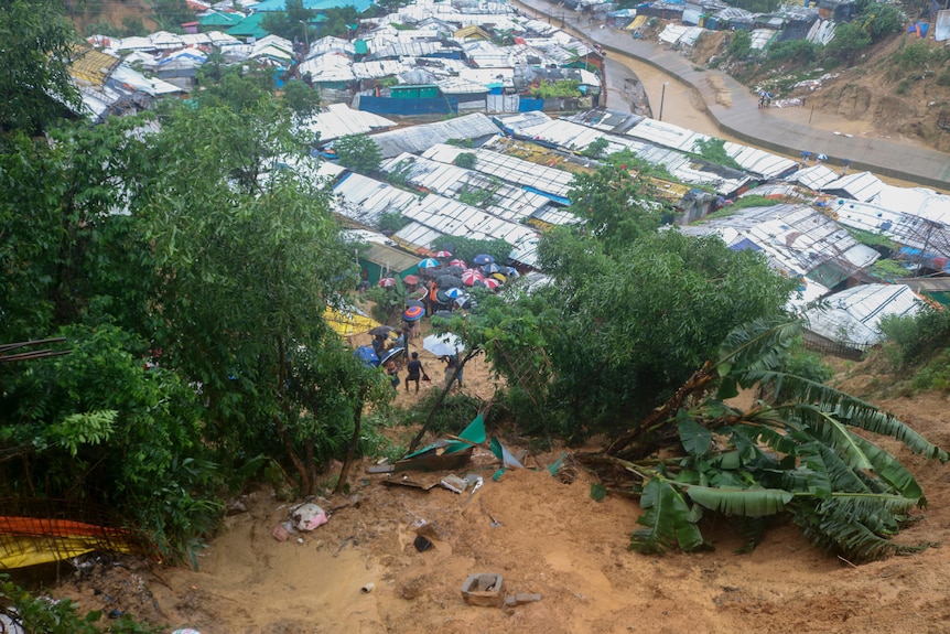 Rohingya refugees and others hold umbrellas as they search for survivors after a landslide