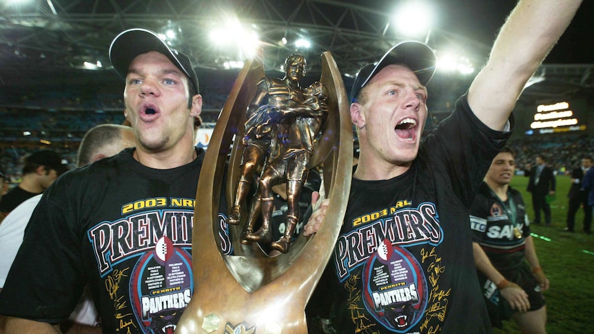 Penrith Panthers Luke Rooney and Luke Lewis hold the NRL premiership trophy after the 2003 grand final against the Roosters.