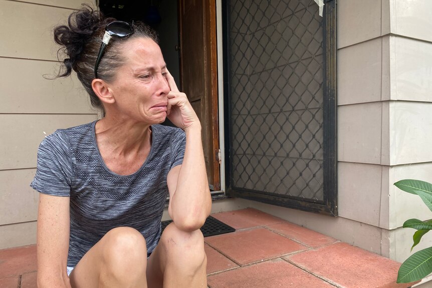 A woman sitting on her porch crying.