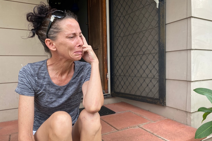 A woman sitting on her porch crying.