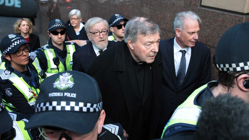 George Pell arrives at court with his lawyer, Robert Richter, surrounded by police.