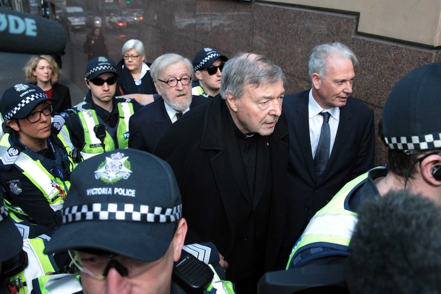 George Pell arrives at court with his lawyer, Robert Richter, surrounded by police.