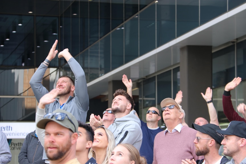 People looking up and clapping and waving.