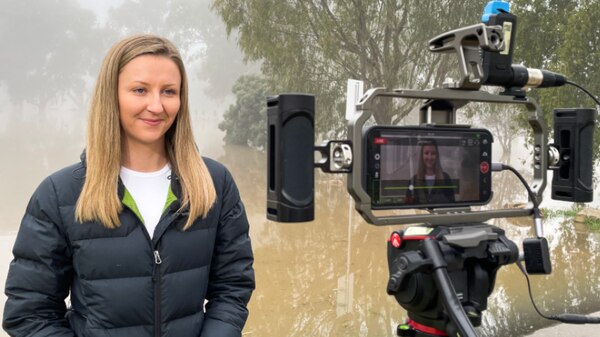 Photo of a reporter facing a camera which is filming her