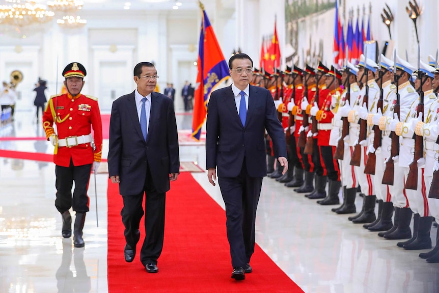 China's Premier Li Keqiang and Cambodia prime minister Hun Sen walk side by side on a red carpet.