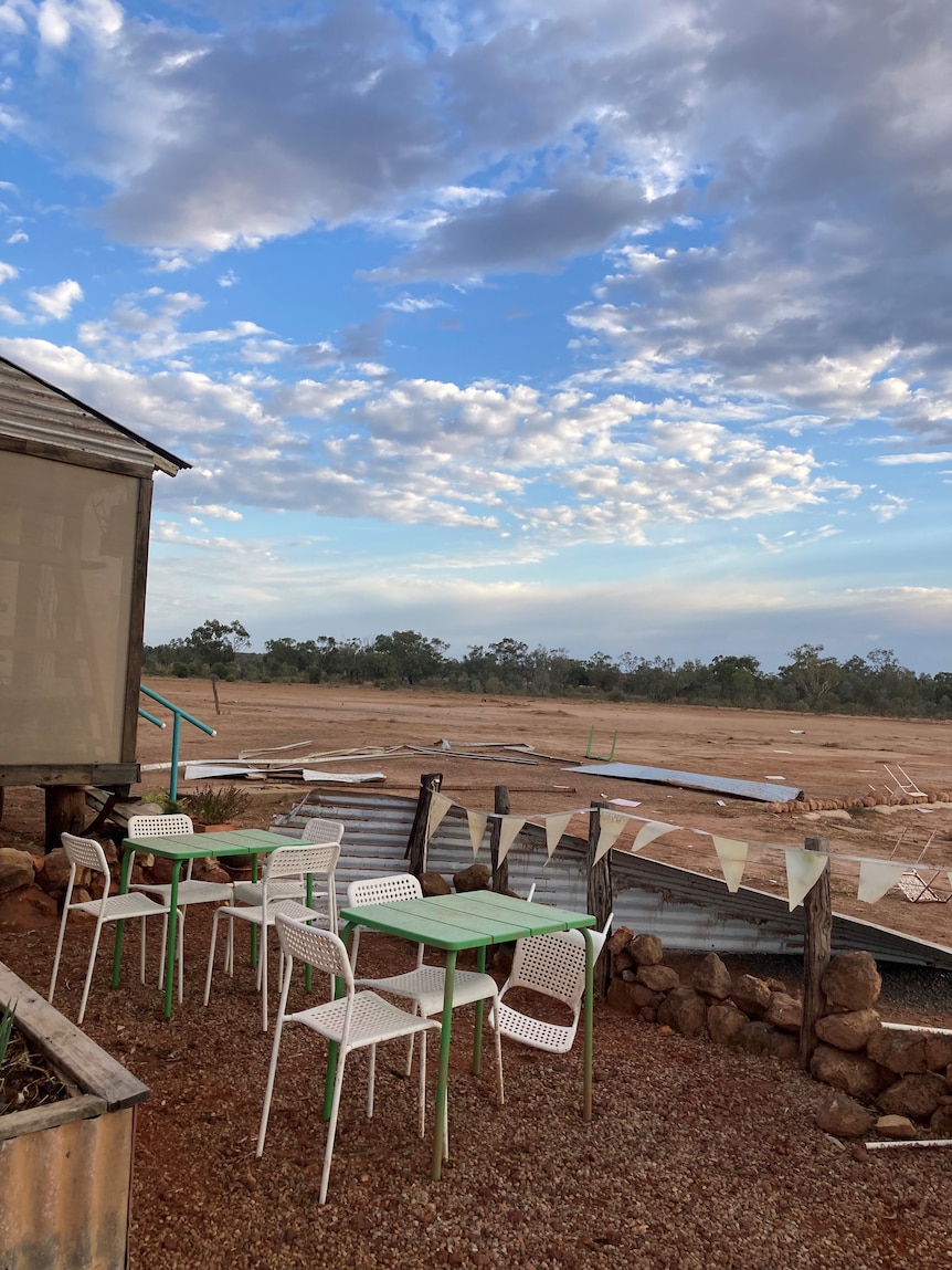 An outdoor seating area at a cafe which has been destroyed by a storm. Debris sits in the background.
