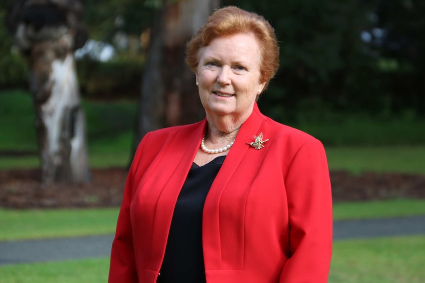 Cheryl Edwardes poses for a picture outdoors wearing a red jacket and black blouse.