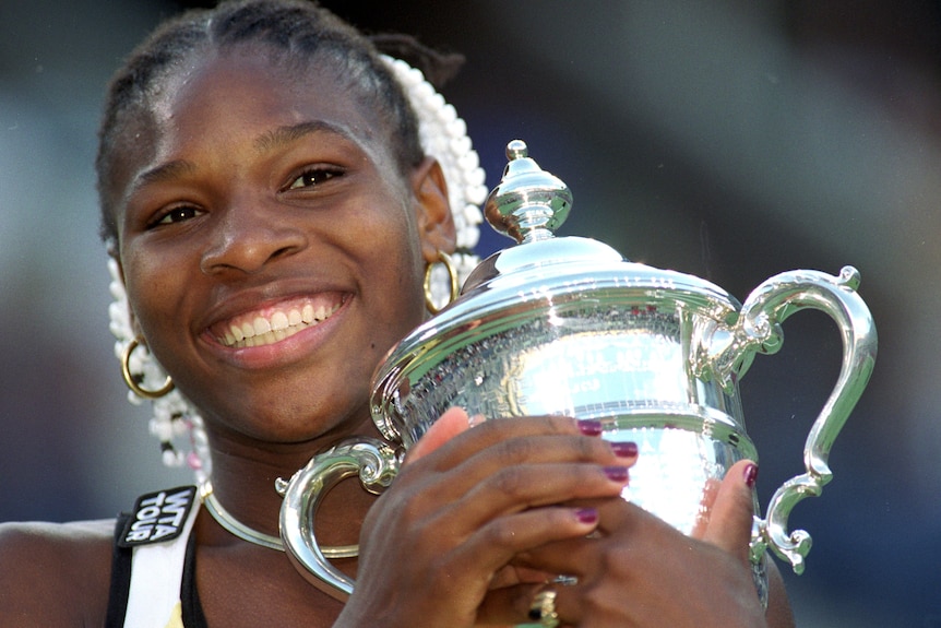 Serena Williams smiles as she holds the US Open trophy after the 1999 women's final.