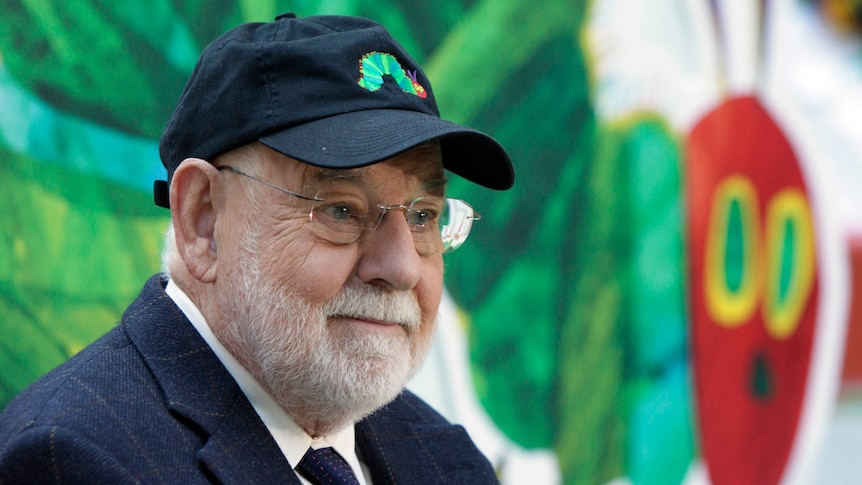 Author Eric Carle with the iconic picture of his book, The Very Hungry Caterpillar in the background
