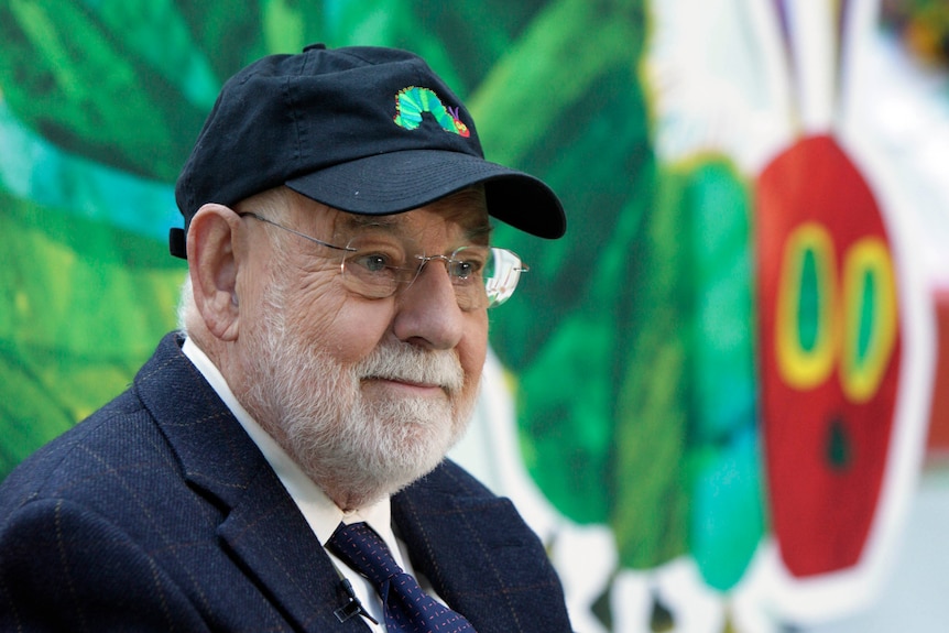 Author Eric Carle with the iconic picture of his book, The Very Hungry Caterpillar in the background