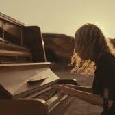 A woman with long hair playing a piano in the open air 