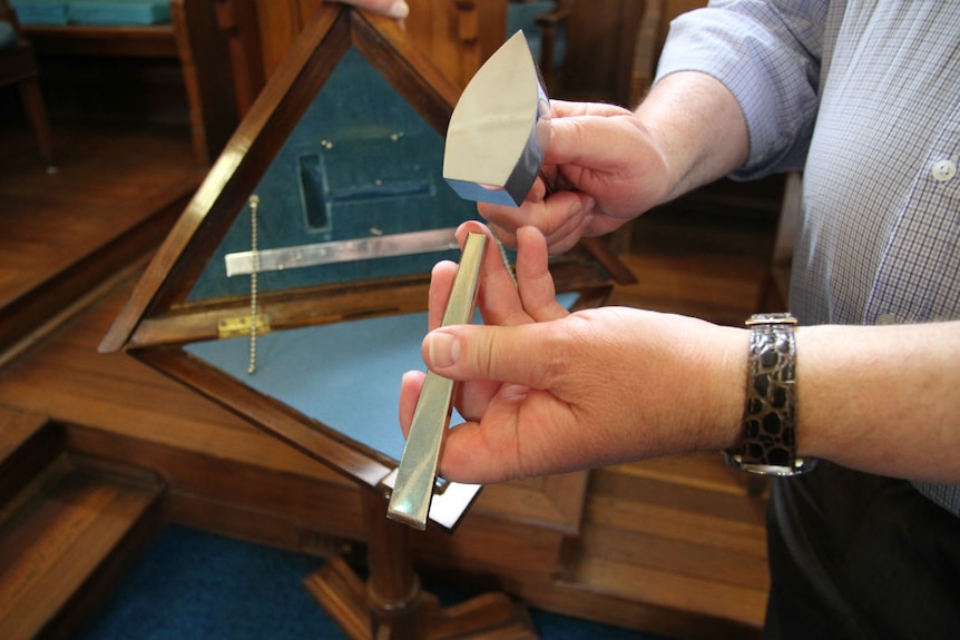 Hands holding a metal hammer and other instruments.