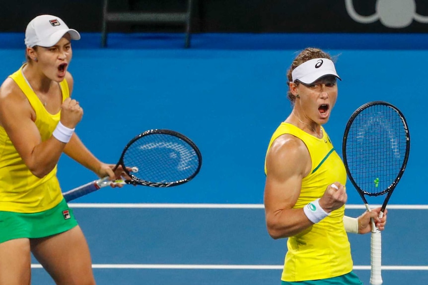 Sam Stosur and Ash Barty pump their fists while playing doubles tennis for Australia in the Fed Cup semi-final against Belarus.