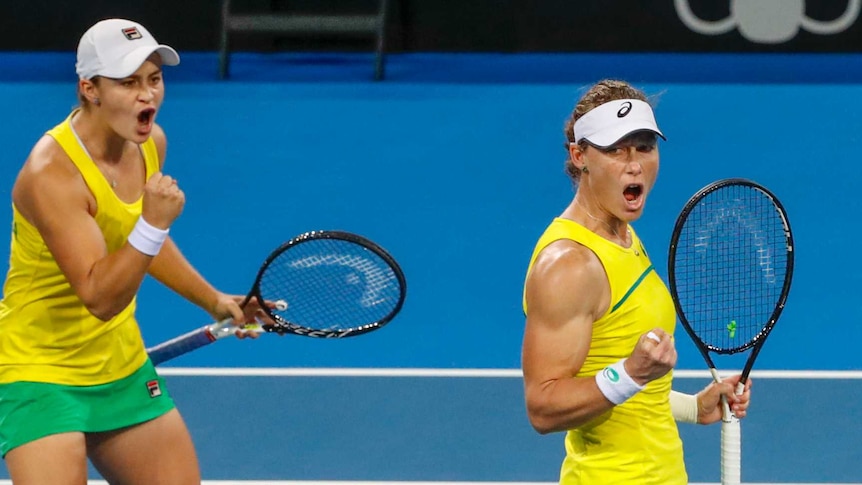 Sam Stosur and Ash Barty pump their fists while playing doubles tennis for Australia in the Fed Cup semi-final against Belarus.