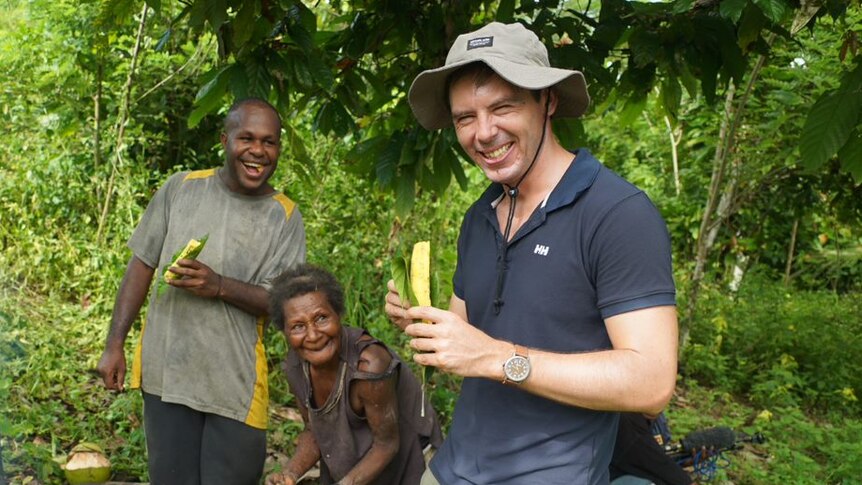 Eric Tlozek eats locally grown food with some Papua New Guineans