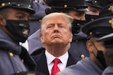 Former president Donald Trump is surrounded by army cadets while watching a football game.