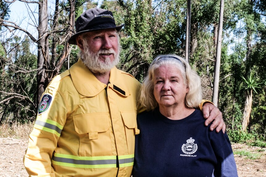 Couple in RFS uniform standing on cleared property with with arms around each other