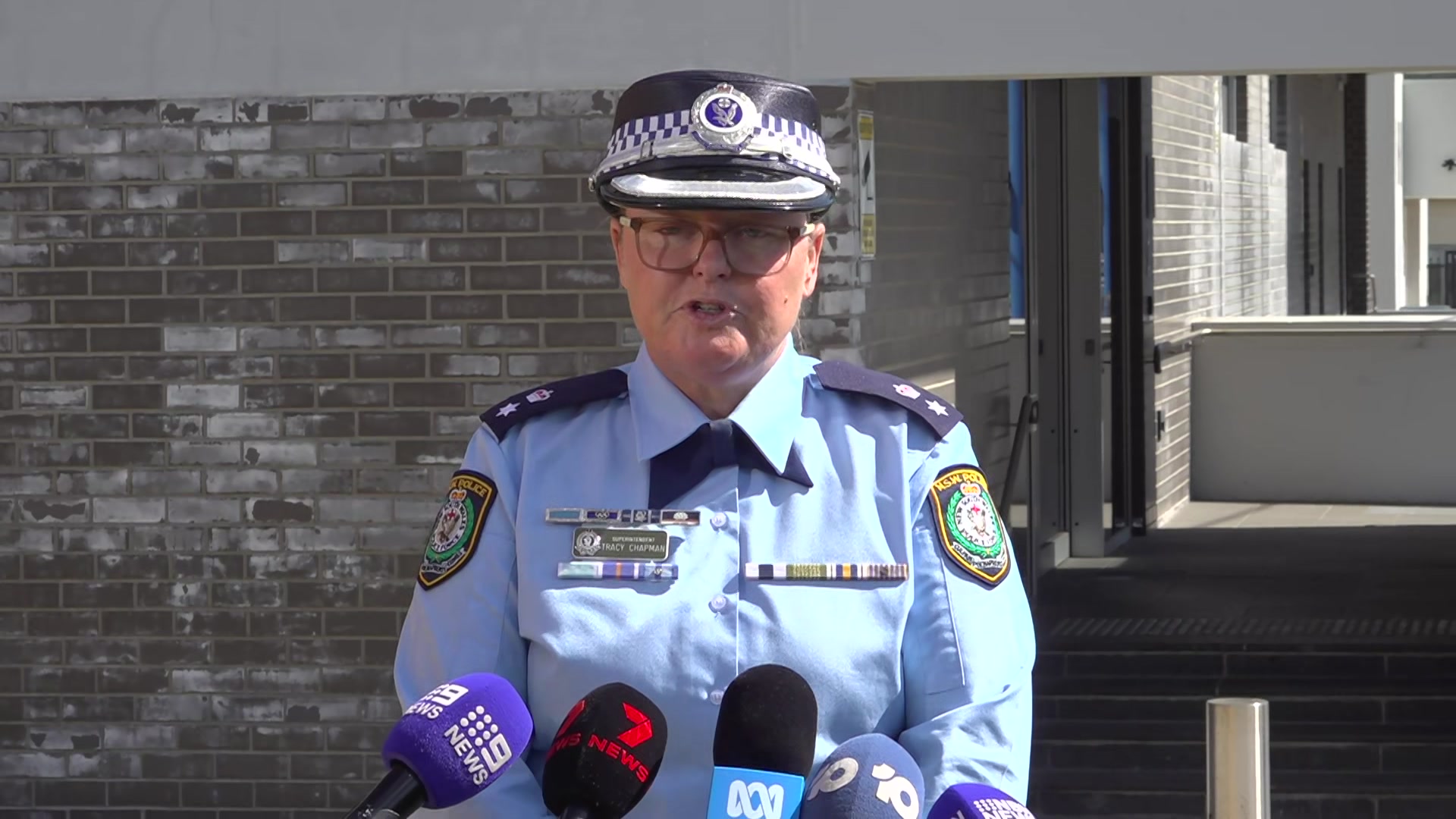   تريسي تشابمان يرتدي زي الشرطة الأزرق ويتحدث في مؤتمر صحفي.